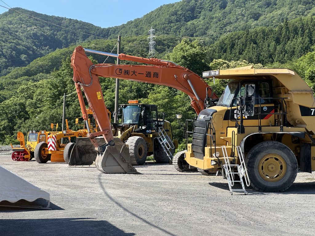 採石場見学会「ヒーローアカデミー」の会場に並ぶ重機と手前に展示されたグループ会社の建設用重機